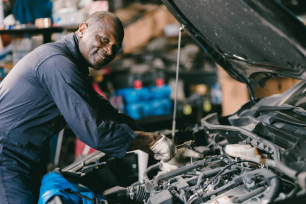 happy smiling mechanic male car engine service underhood checking oil replace in broken part at auto garage stock photo