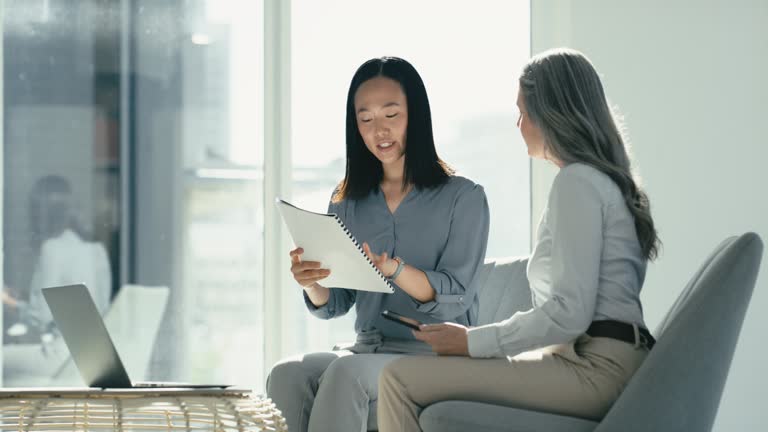 Asian business woman in a meeting with a coworker planning and talking about company financial growth portfolio. Corporate females only having a discussion about investment strategy in an office