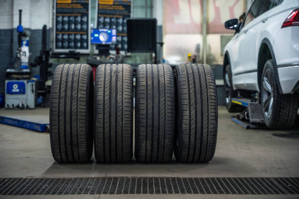 Set of used and dirty summer tires at tire service and car on a lift stock photo