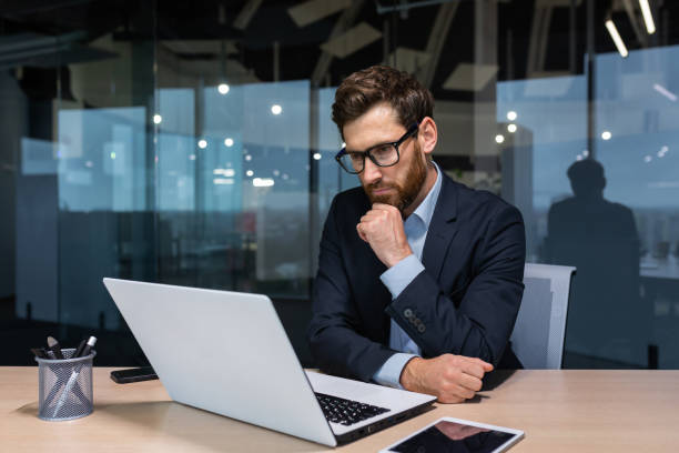 istock Serious thinking businessman working inside office building, man pondering important decision, boss in business suit using laptop at work 1434635962