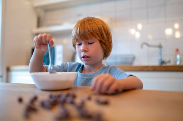 istock Cute ginger little boy sitting at the table and eating cereals 1434637277