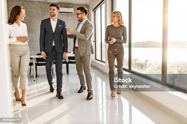 Happy Business Colleagues Talking On The Move In The Office Stock Photo - Download Image Now