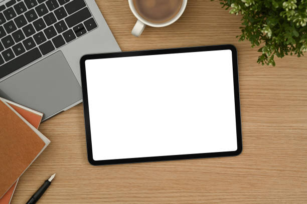 istock Digital tablet with white empty screen, laptop, notepad and coffee cup on wooden desk. 1434644764