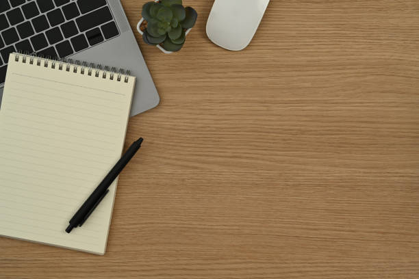 istock Top view blank notepad, laptop computer, mouse and potted plant on wooden working desk. Copy space for your text. 1434644772