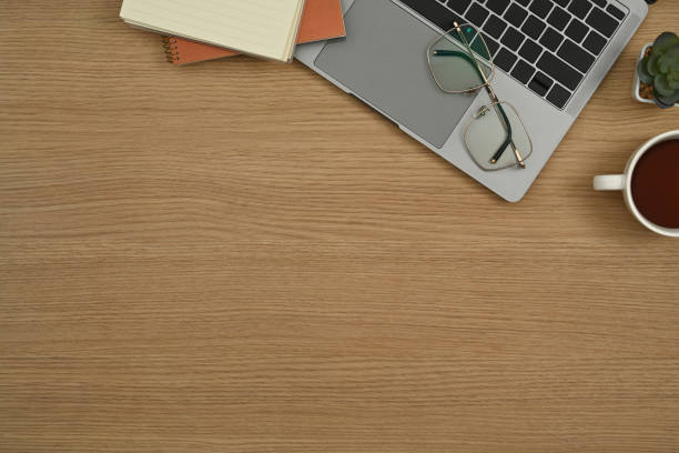 istock Simple workplace with laptop computer, glasses, notepad and cup of coffee on wooden background. 1434644796