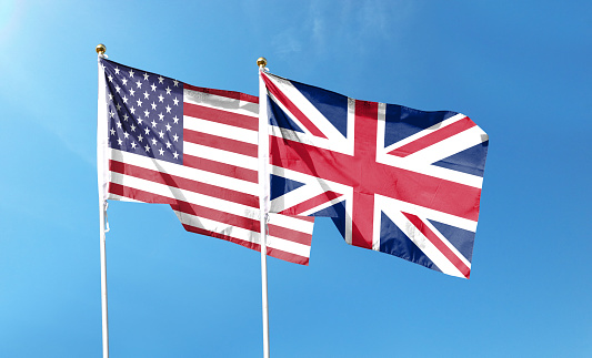 American flag and British flag on cloudy sky. waving in the sky