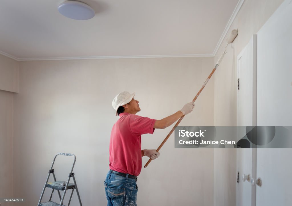 Man painting wall with a roller in home renovation project Painting - Activity Stock Photo