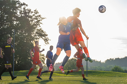 Teenage girls tackling during the soccer match on a playing field.