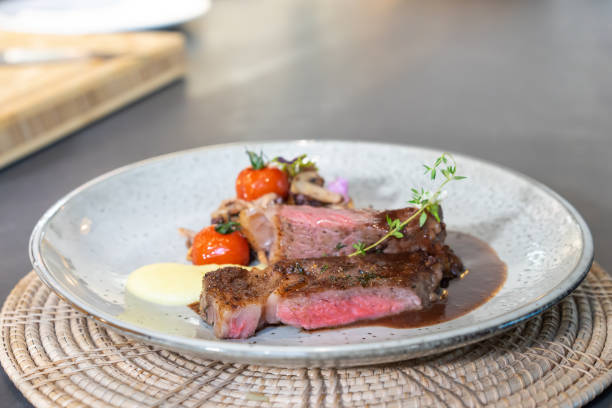istock Medium Rare Beef Steak was grilled and fried with sliced mushroom and mini tomato on white dish, ready to serve and eat. 1434650920