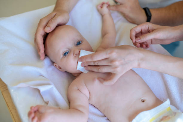 istock Mom cleaning babys nose with a napking while doctors examining 1434650929