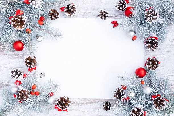 istock Stylish Christmas frame with snow-covered spruce branches, cones and Christmas decorations in white and red colors. Beautiful new year design template with white sheet of blank paper for copy space. 1434651947