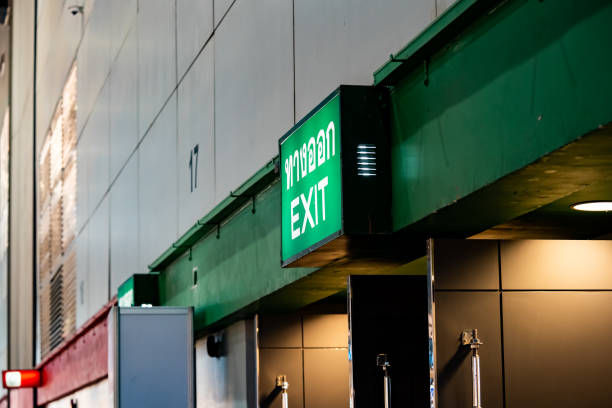 istock Large Emergency exit sign green light box is placed on the wall of exhibition hall. Thai Letter is Thai Language on the green light box mean EXIT. 1434652179