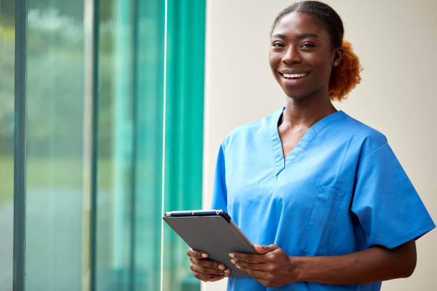 Portrait Of Smiling Female Nurse Or Doctor Wearing Scrubs With Digital Tablet stock photo