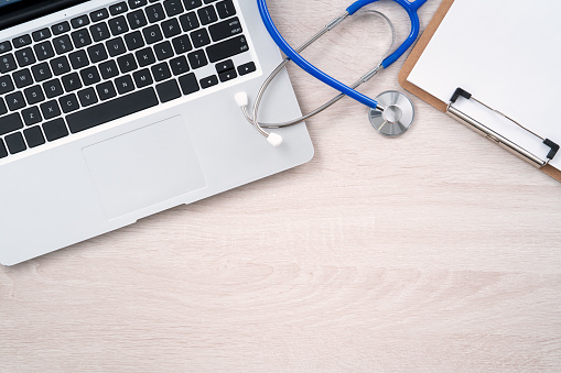 Doctor diagnoses design concept - stethoscope on computer keyboard with medical record clipboard on white working table.