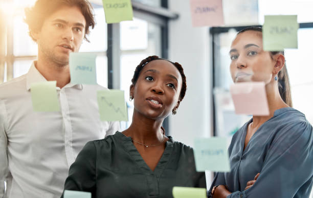 istock Teamwork collaboration, planning strategy ideas and marketing solution in information meeting, vision and glass wall in creative agency. Diversity business people, thinking and working schedule notes 1434660412