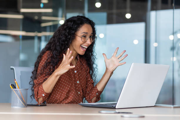 젊은 히스패닉 비즈니스 여성은 좋은 직장 결과를 얻었고, 비즈니스 여성은 행복하고 노트북 화면에서 손을 들고 읽는 승리를 축하합니다. - celebration success business computer 뉴스 사진 이미지