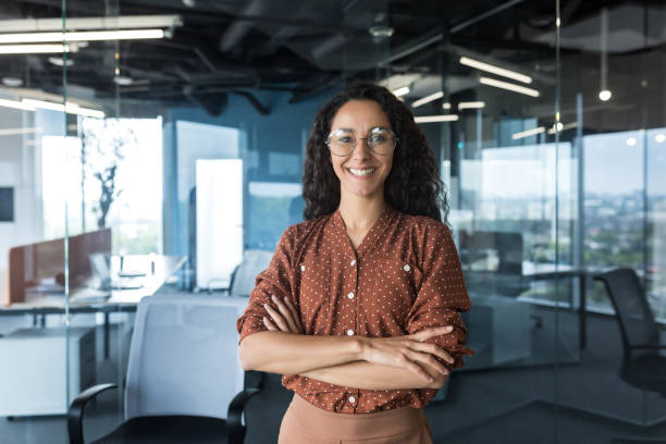 istock Young successful Indian IT developer female engineer working inside the office of a development company portrait of a female programmer with curly hair and glasses, smiling and looking at the camera 1434661655