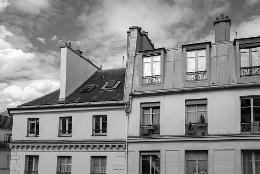 A low-angle grayscale of a France home facade, gloomy, cloudy sky background