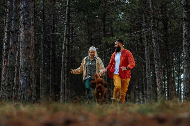 istock Couple with dog running in forest. 1434670268