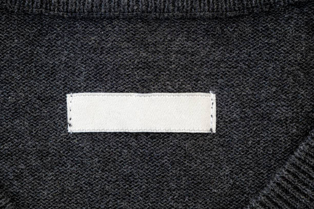 Blank stripe, label for branding on sweater. Tag mockup on gray cloth, top view.