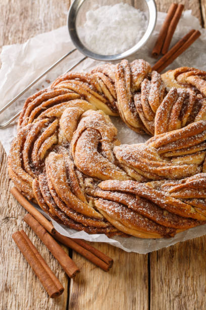 istock Estonian Kringle Cinnamon Braid Bread with powdered sugar closeup on the paper. Vertical 1434675900