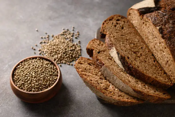 Sliced loaf of Hemp bread and hempseeds on brown background. Close up.
