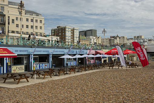 Boardwalk and cafes on the seafront promenade and beach at Brighton in East Sussex, England