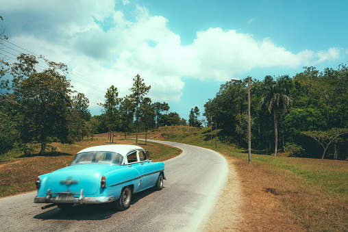 Blue vintage car driving on rural road, Cuba