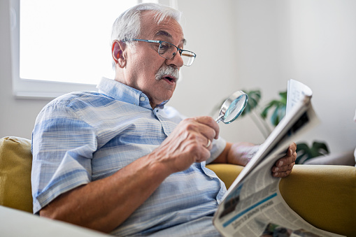 Senior man holding an magnifying for reading