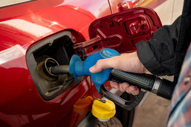 un uomo che tiene la pompa che riempie la benzina. pompando benzina nel serbatoio. un'auto fa rifornimento sulla stazione di servizio - pompa daria foto e immagini stock