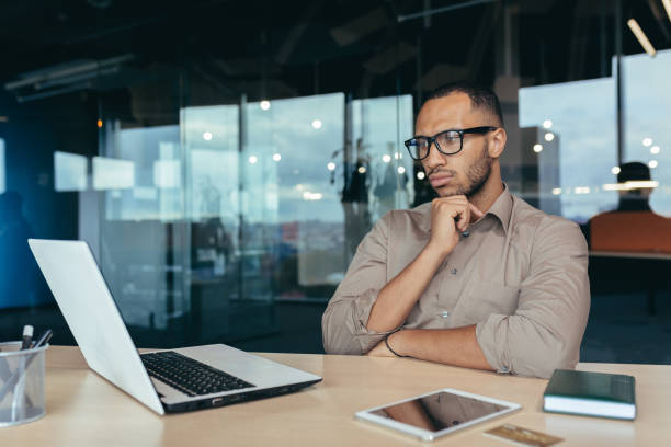 istock Thinking Hindu businessman in glasses, male programmer developer working inside office of modern product IT company, entrepreneur at work with laptop 1434688191