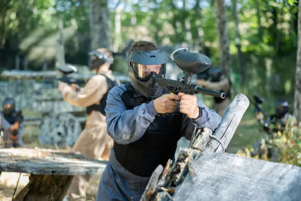 Man aiming with paintball market on battleground. Competitive shooting sport.