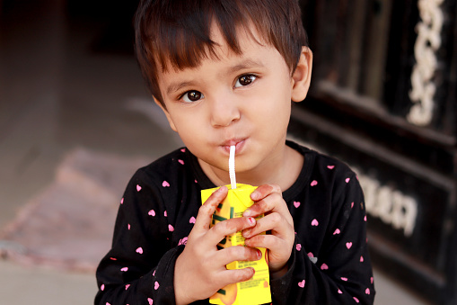 Small girl drinking Frooti tetra drink.