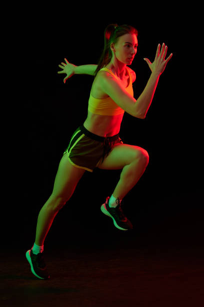 istock Running technique. Professional female jogger running isolated on dark background in neon light. Sport, fitness, speed and energy concept. 1434691752