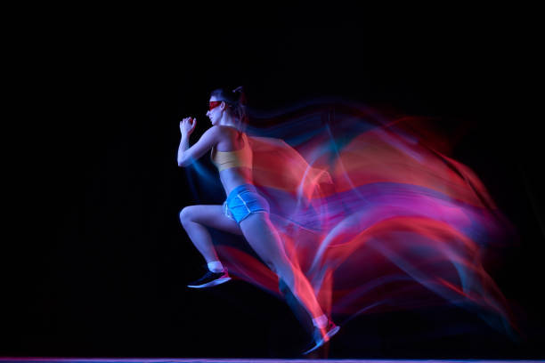 istock Professional female athlete, runner in motion over dark background in mixed neon light. Art, beauty, sport, cyberpunk concept 1434691783