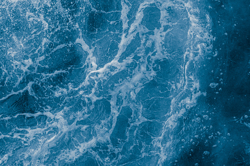 Superficie de mar azul oscuro con olas, salpicaduras y burbujas photo