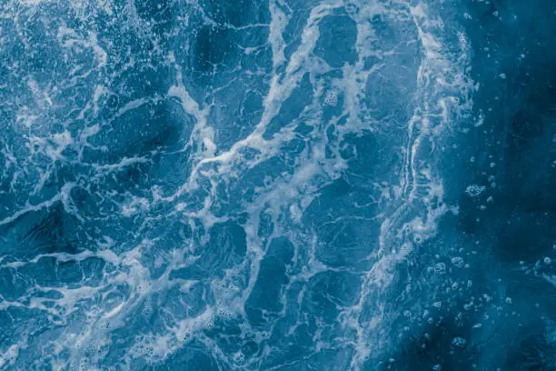 Photo of Dark blue sea surface with waves, splash and bubbles