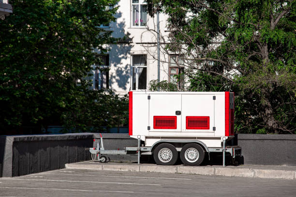istock White and red Backup Generator on the trailer with wheels. Mobile emergency Generator or Standby Generator - Outdoors Power Equipment on the street nearby trees and building on sunny day, nobody. 1434696711