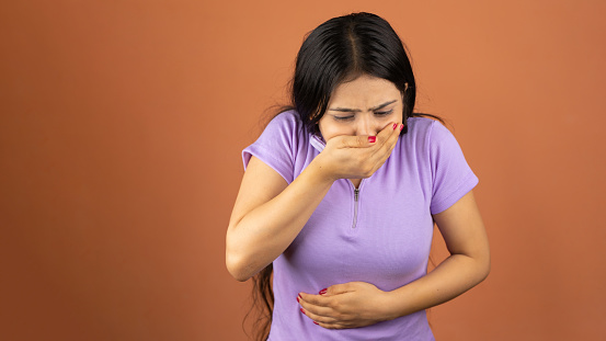 Woman suffering from stomach ache and nausea on color background