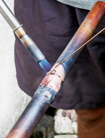A worker is soldering copper pipes