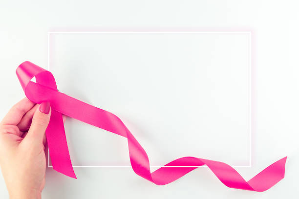 fond de ruban rose. symbole des soins de santé ruban rose dans les mains de la femme sur fond blanc. concept de soutien au cancer du sein. journée mondiale contre le cancer. - surgical pin photos et images de collection