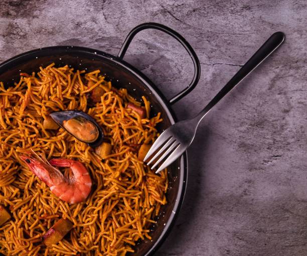 primer plano de la fideua valenciana con tenedor sobre fondo gris - fideua fotografías e imágenes de stock