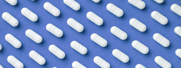istock Blue medicine background with white pills and tablet, macro. Drug production backdrop. 1434708458