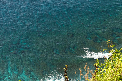High angle view of the transparent turquoise waters at the remote Suwehan bay, on the south coast of Nusa Penida island, Bali, Indonesia