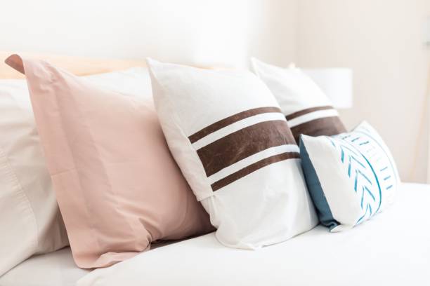 istock White bed with pink and blue, brown striped pillows 1434712938