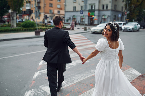 On the crosswalk. Beautiful bride with his fiance is celebrating wedding outdoors.