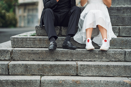 Sitting on the stairs. Beautiful bride with his fiance is celebrating wedding outdoors.