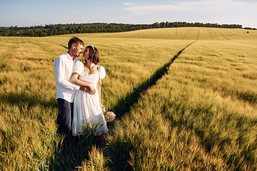 Standing and enjoying the nature. Couple just married. Together on the majestic agricultural field at sunny day.