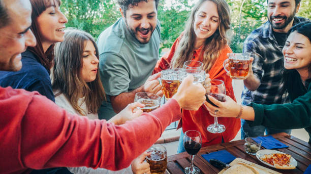 Group of friends toasting beer and wine glasses together stock photo
