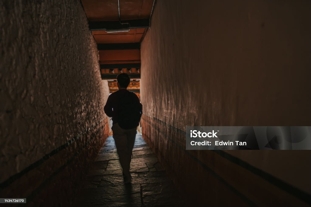 Rear View solo female traveller walking in corridor of Punakha Dzong Dark Stock Photo